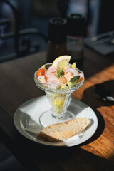 Appetizer prawn cocktail with vegetables served with brown bread in a glass