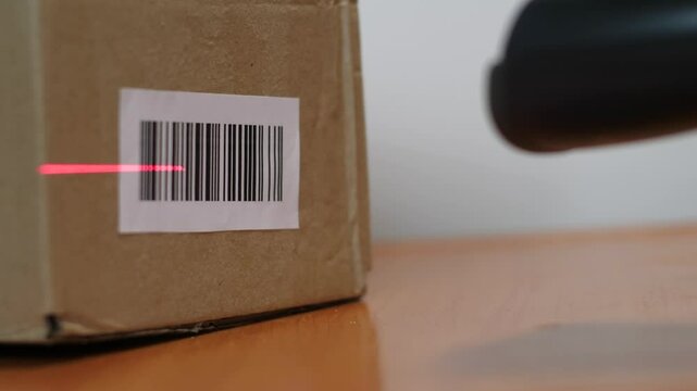 close-up of the parcel barcode being scanned with a barcode scanner at a pick-up point or logistics center, a box with goods being scanned by barcode