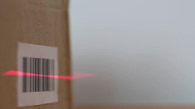 close-up of the parcel barcode being scanned with a barcode scanner at a pick-up point or logistics center, a box with goods being scanned by barcode