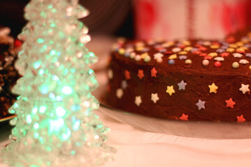 Christmas tree decoration and colorful cake on the holiday table. Selective focus.
