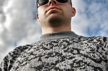 Obraz premium 灰色のセーターを着た男性が青空を背景に立っている姿