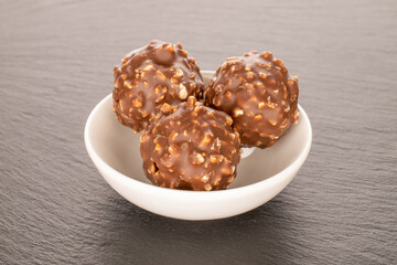 Chocolate candies with hazelnuts on slate stone, close-up.