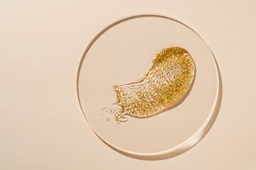 Liquid gel gold. transparent gel liquid with golden glitter In a Petri dish on beige background. Laboratory research of cosmetics, gel, medicine. Chemistry sample testing