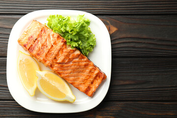 Delicious grilled salmon fillet served on wooden table, top view