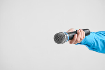 Woman with microphone on grey background, closeup. Space for text