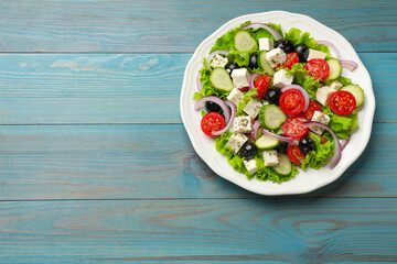 Delicious salad with feta cheese on light blue wooden table, top view. Space for text