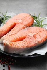 Fresh raw salmon steaks and spices on grey table, closeup