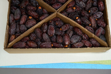 Close-Up of Fresh Dates in Cardboard Boxes. Neatly arranged fresh, ripe dates in a sectioned cardboard box, highlighting healthy, natural dried fruit ready for consumption.

