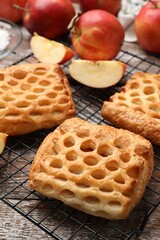 Delicious puff pastries with fruit filling and apples on wooden table, closeup