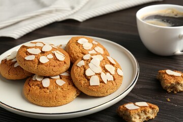 Tasty cookies with almond flakes and coffee on wooden table, closeup