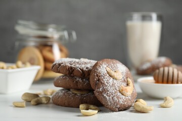 Tasty chocolate cookies with cashew and powdered sugar on white table, closeup
