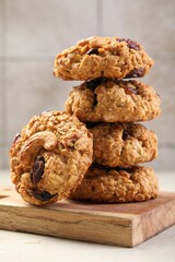 Delicious oatmeal cookies with raisins and nuts on light grey table, closeup