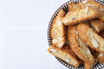 Traditional Italian almond biscuits (Cantucci) in bowl on white table, top view. Space for text