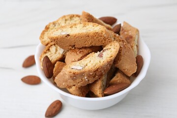 Tasty almond biscuits (Cantuccini) and nuts in bowl on white table, closeup