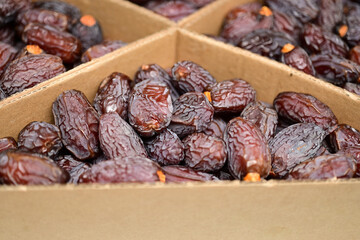 Close-Up of Fresh Dates in Cardboard Boxes. Neatly arranged fresh, ripe dates in a sectioned cardboard box, highlighting healthy, natural dried fruit ready for consumption.

