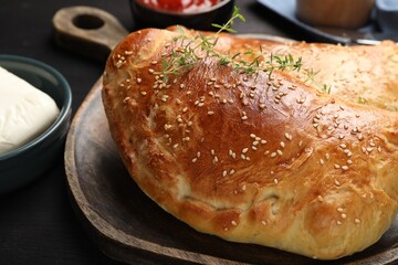 Delicious fresh calzone pizza served on wooden table, closeup