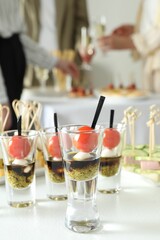 Many different tasty canapes on white table. People enjoying buffet meals indoors, closeup