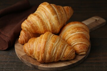 Tasty fresh croissants on wooden table, closeup. Puff pastry