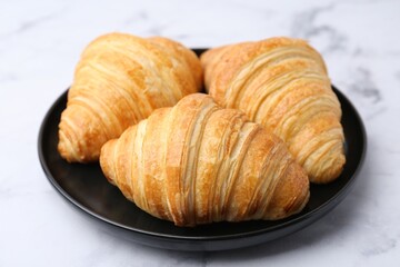 Tasty fresh croissants on white marble table, closeup. Puff pastry