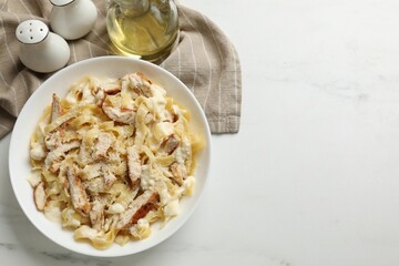 Tasty Alfredo pasta with chicken on white marble table, flat lay. Space for text