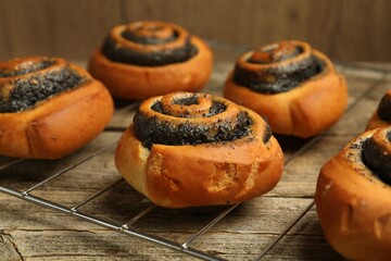 Tasty bun with poppy seeds on wooden table, closeup