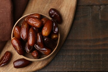 Tasty sweet dried dates in bowl on wooden table, top view. Space for text