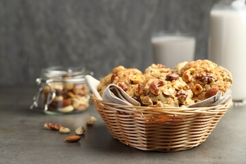 Tasty cookies with nuts in wicker basket on grey table, closeup. Space for text