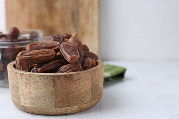 Tasty dried dates on white tiled table, closeup. Space for text