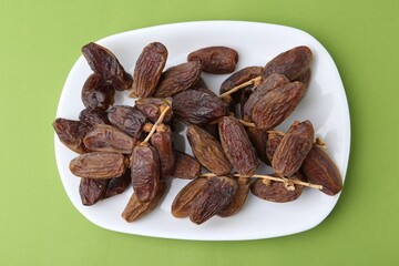 Tasty dried dates on green background, top view