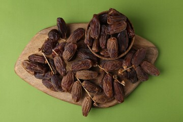Tasty dried dates on green background, top view