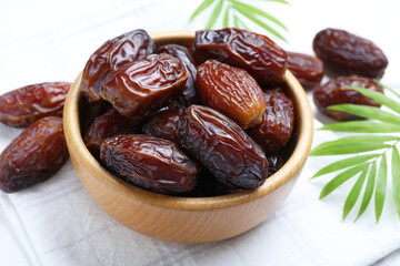 Tasty dried dates and leaves on white table, closeup