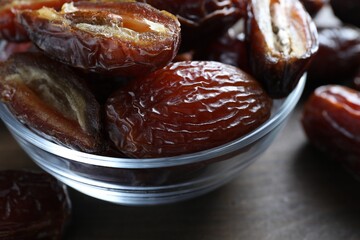 Many tasty dried dates in bowl on table, closeup