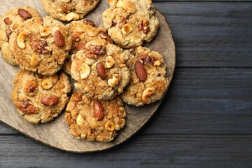 Tasty cookies with nuts on dark wooden table, top view. Space for text