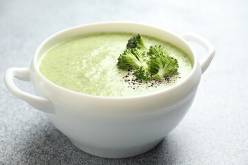 Delicious broccoli cream soup in bowl on light table, closeup