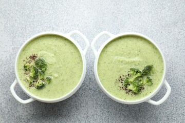 Delicious broccoli cream soup in bowls on light table, top view