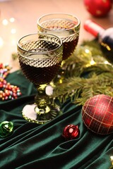 Glasses with red wine and beautiful Christmas decor on table, closeup