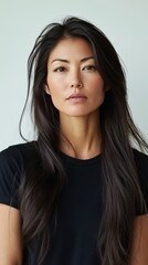 Fototapeta premium Portrait of a woman with long dark hair and striking features in a simple black top