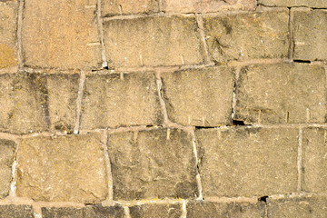 Textured stone wall displays various weathering patterns formed over time, highlighting the craftsmanship involved in constructing this historical structure in a remote area