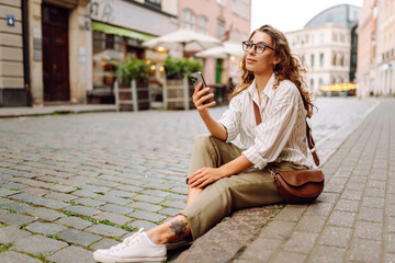 Happy woman using phone walking in city street. Communication, social networks, blogging, online shopping concept.