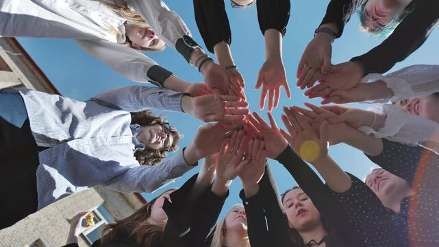 Students coming together in a circle, uniting in teamwork and solidarity on a sunny school day