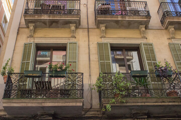 facade of a building with balconies and windows with shutters; there is a table and chairs on the balconies