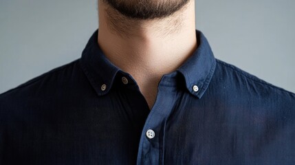 Obraz premium Modern navy blue shirt with button details displayed against a neutral background focusing on the collar and neckline of the garment.