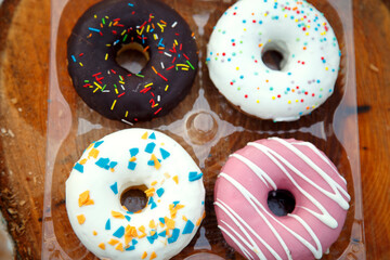 A selection of freshly baked donuts in multi-colored glaze. Beautiful sweet donuts with sprinkles. Dessert close-up. 