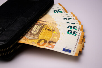 Black leather wallet with fifty euro bills banknotes on white background 