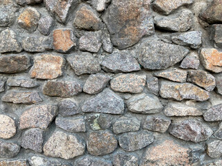 Close-up view of an old, natural dry-stone wall with varied rock sizes and shapes, no visible...