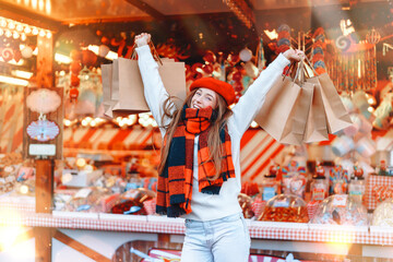 Joyful shopper celebrates with festive bags at a cheerful holiday market