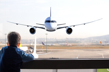 A tourist kid waits for his flight at the airport. Curious boy watches the plane take off. Air...