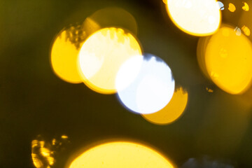 A soft and blurry visual display of yellow and white lights lit against a deep dark background,...