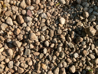 Close-up of uneven, light graybrown pebbles in natural rock formation with daytime lighting