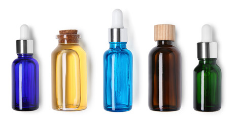 Essential oils in different bottles on white background, top view